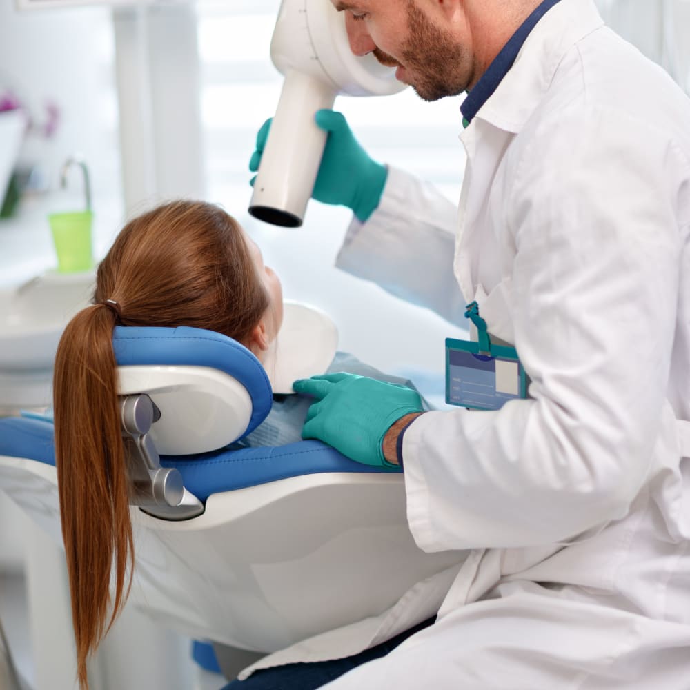 A dentist prepares to take a digital X-ray of a patient's mouth.